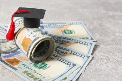 Photo of Scholarship concept. Graduation cap and banknotes on light grey table, closeup