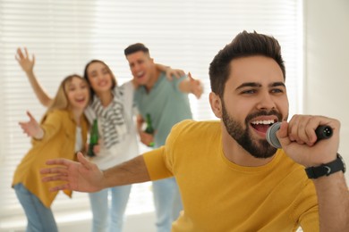 Young man singing karaoke with friends at home