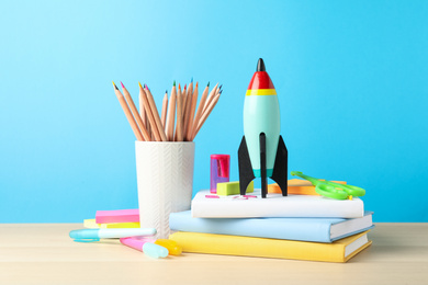 Bright toy rocket and school supplies on wooden table