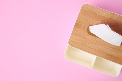 Photo of Holder with paper tissues on pink background, top view. Space for text