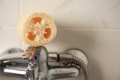 Natural loofah sponge on faucet in bathroom, closeup