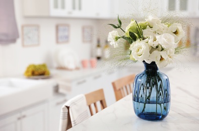 Photo of Bouquet of beautiful eustoma flowers on white table in kitchen. Interior design