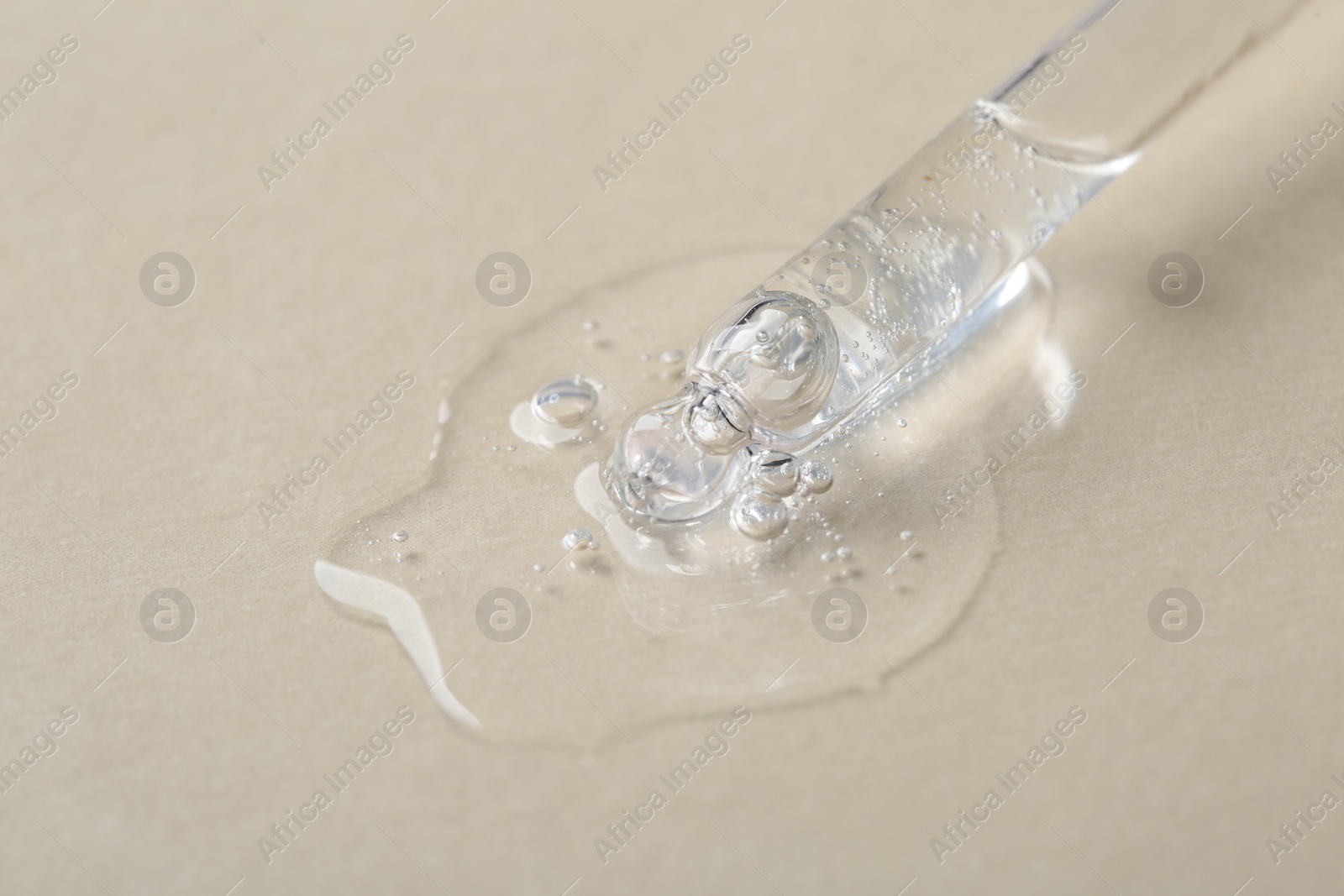 Photo of Pipette with cosmetic serum on beige background, macro view