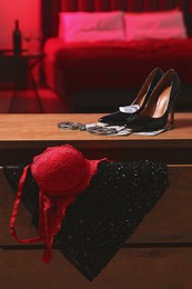 Prostitution concept. High heeled shoes, women`s underwear and handcuffs on wooden chest of drawers indoors