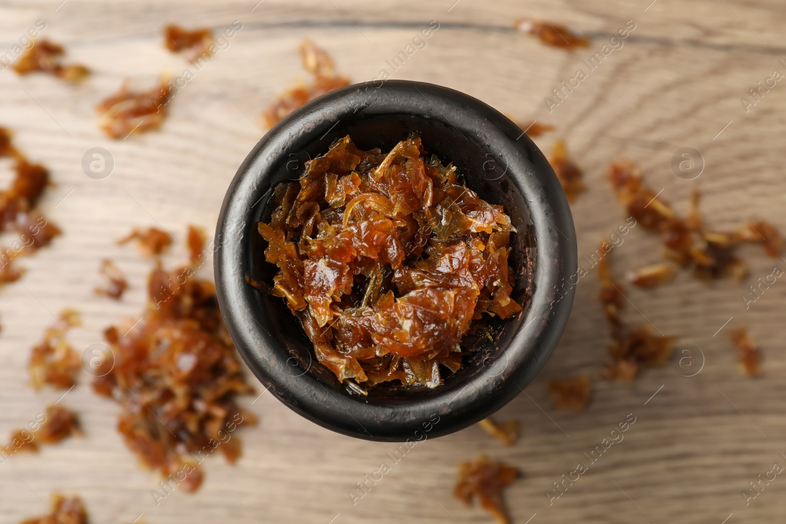 Photo of Clay bowl of hookah with aromatic tobacco on wooden table, top view