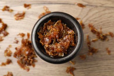 Photo of Clay bowl of hookah with aromatic tobacco on wooden table, top view