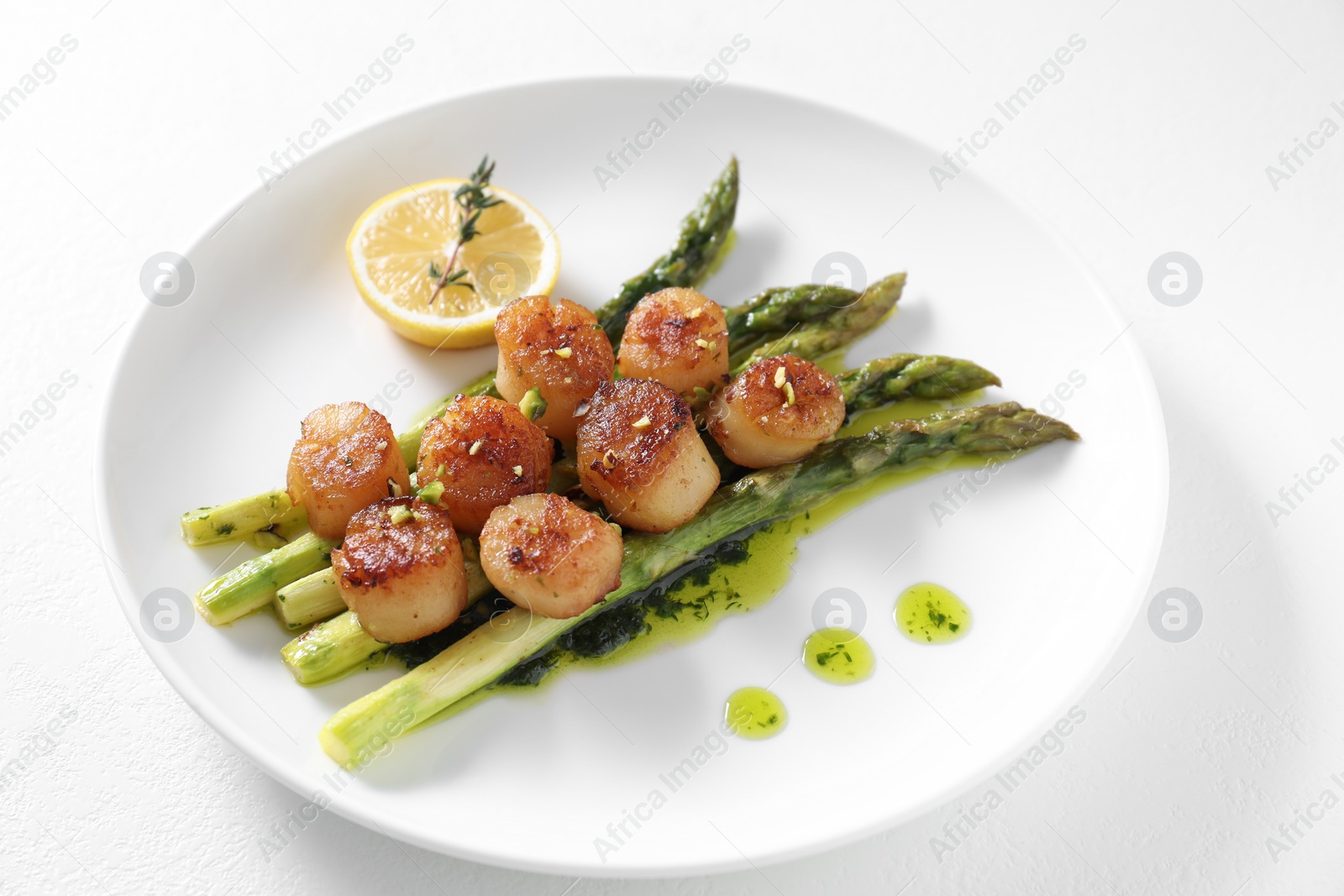 Photo of Delicious fried scallops with asparagus, lemon and thyme on white background