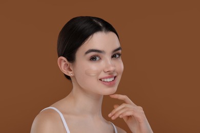 Teenage girl with swatch of foundation on face against brown background