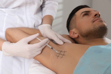 Photo of Cosmetologist injecting man's armpit in clinic. Treatment of hyperhidrosis