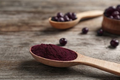 Photo of Spoon with acai powder on wooden table