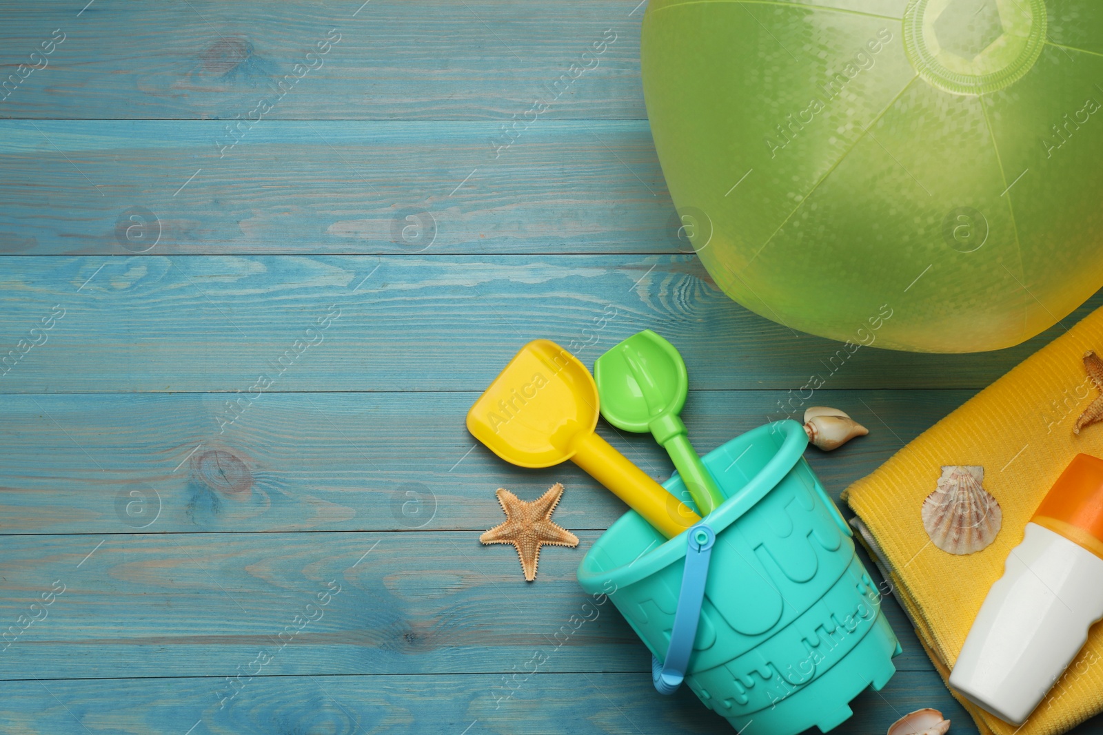 Photo of Flat lay composition with beach ball and sand toys on light blue wooden background. Space for text