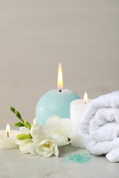 Photo of Beautiful spa composition with burning candle, rolled towel and flowers on white table