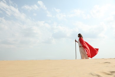 Photo of Jesus Christ walking with stick in desert. Space for text