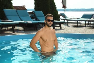 Handsome man in outdoor swimming pool on summer day