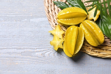 Photo of Delicious carambola fruits on light grey wooden table, flat lay. Space for text