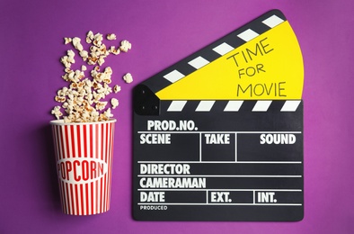 Photo of Flat lay composition with popcorn and cinema clapperboard on color background