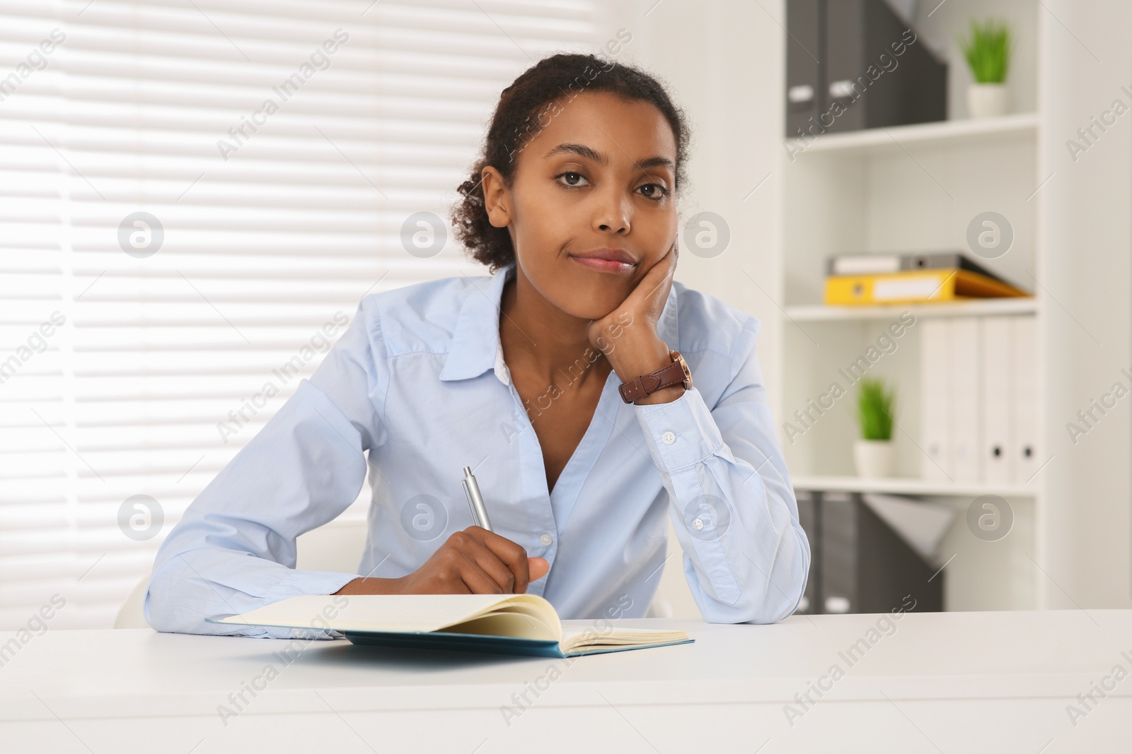 Photo of African American intern working at white table in office