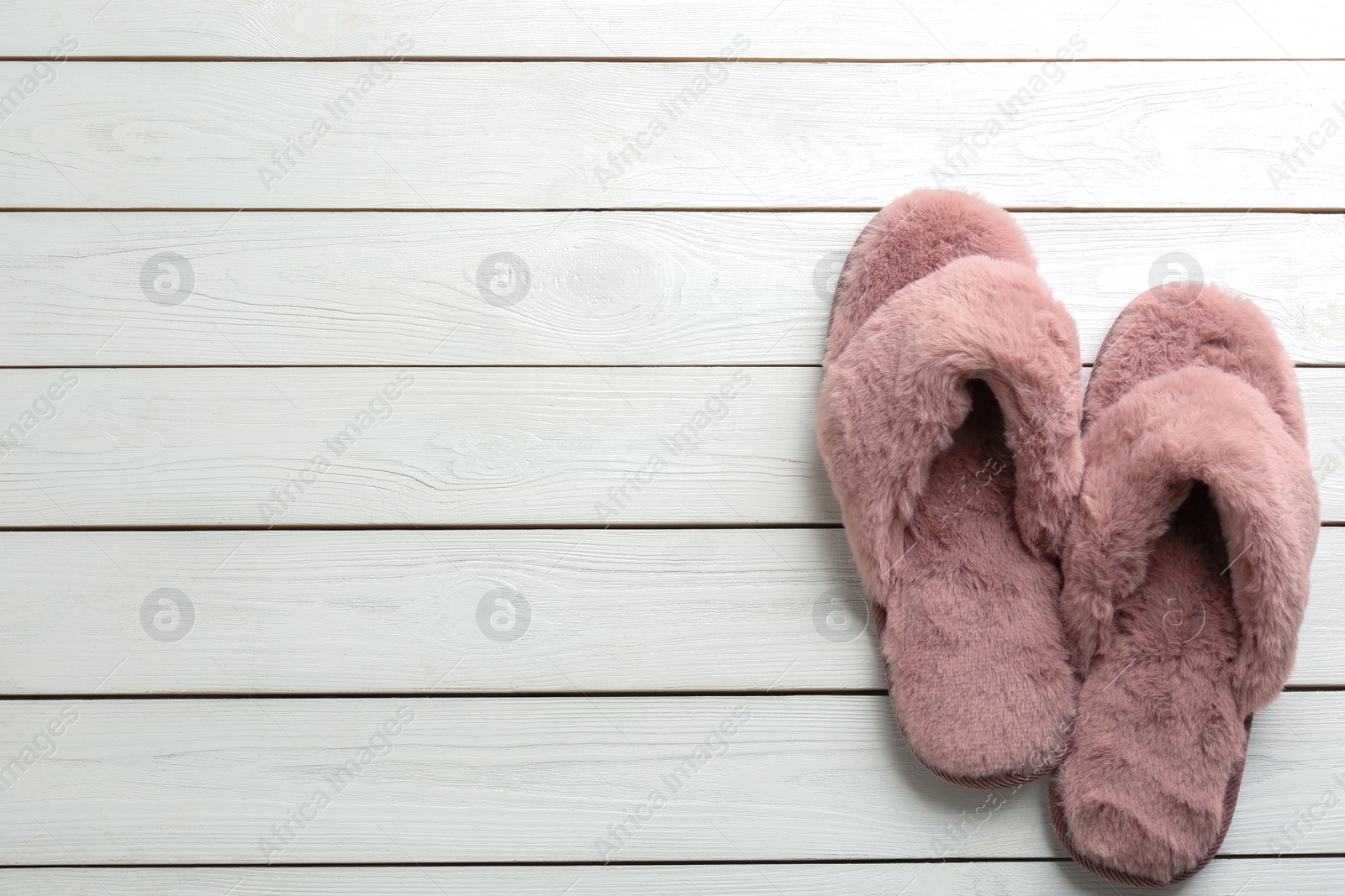 Photo of Pair of stylish soft slippers on white wooden background, flat lay. Space for text