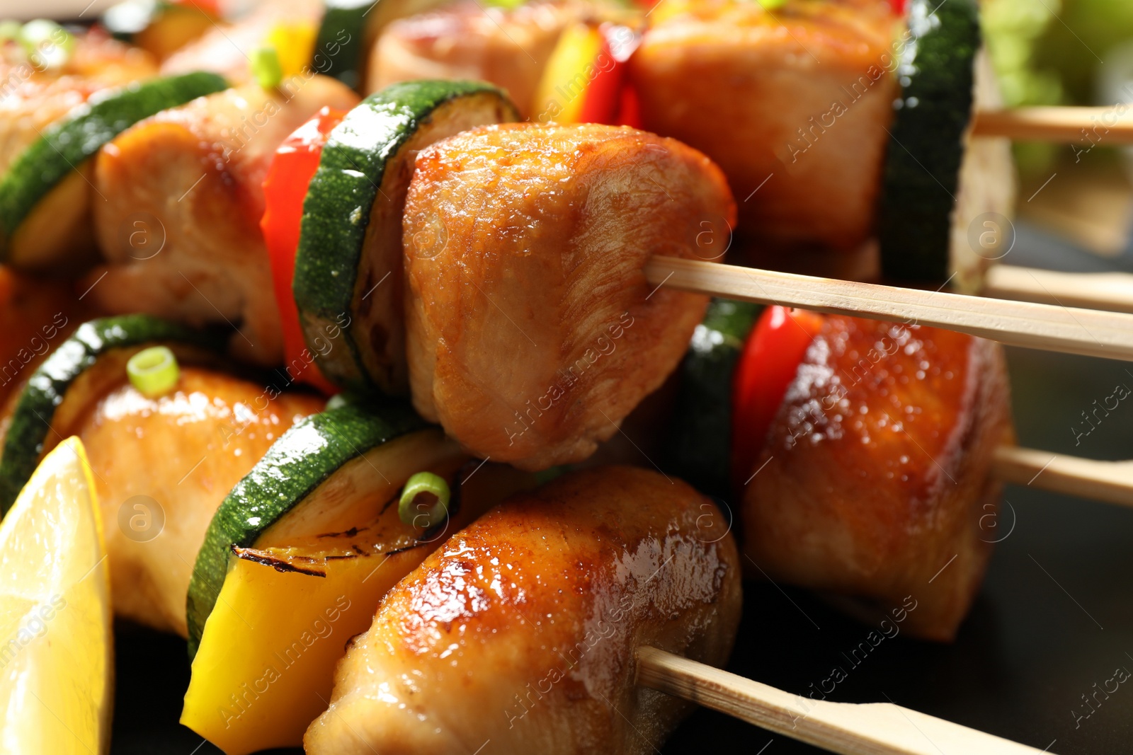 Photo of Delicious chicken shish kebabs with vegetables and lemon on plate, closeup