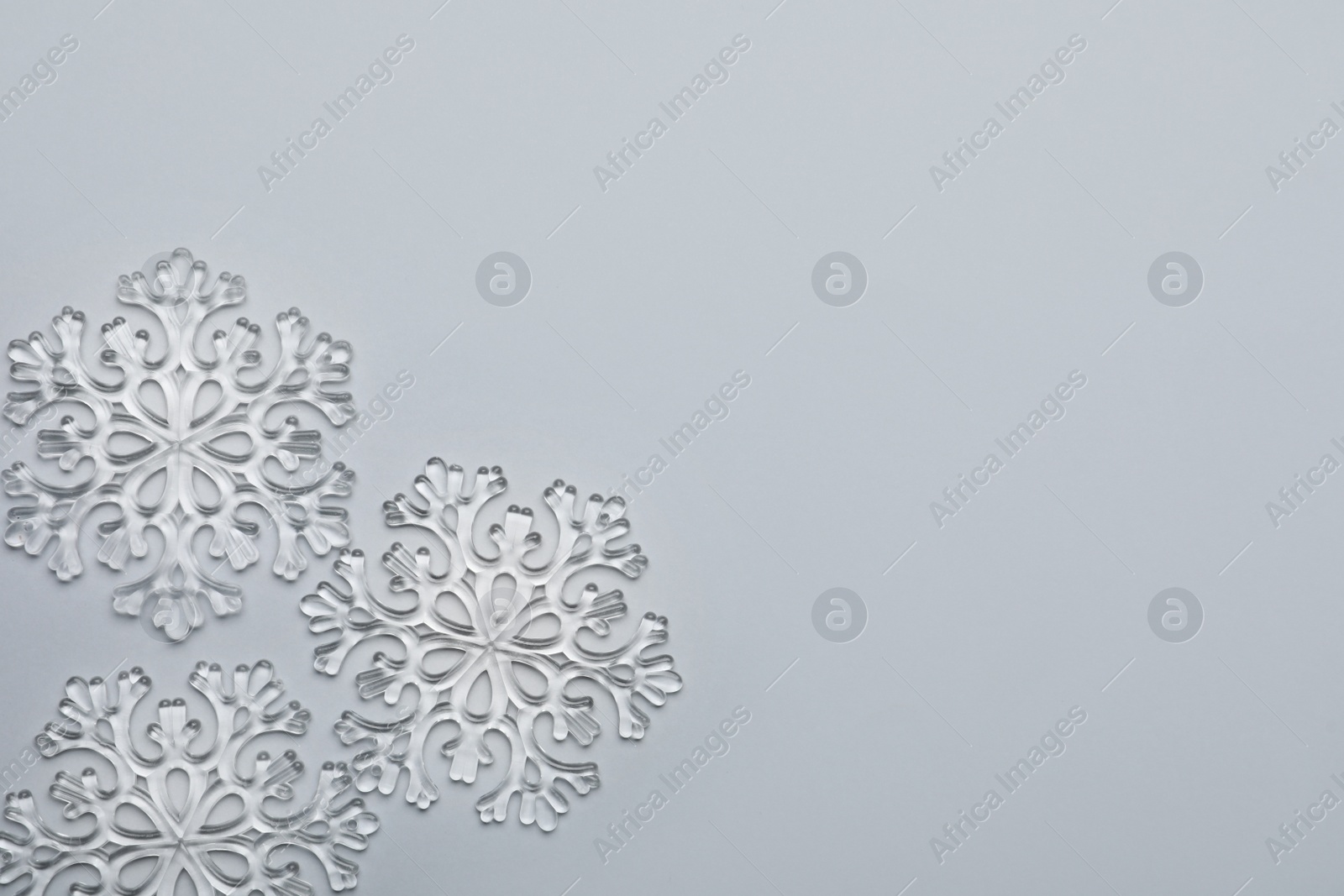 Photo of Beautiful decorative snowflakes on light grey background, flat lay. Space for text