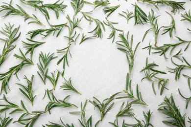 Frame made of fresh rosemary on light table, flat lay. Space for text