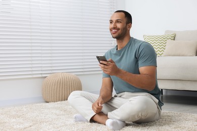 Photo of Happy man with smartphone at home, space for text