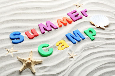 Photo of Composition with phrase SUMMER CAMP made of magnetic letters on sand