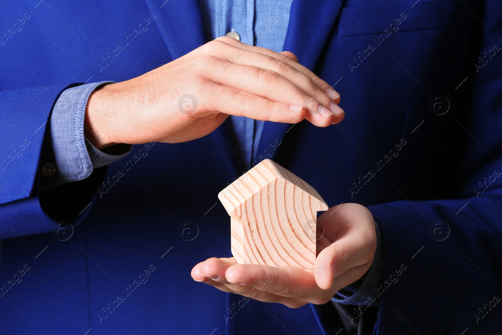 Photo of Male agent covering wooden house, closeup. Home insurance