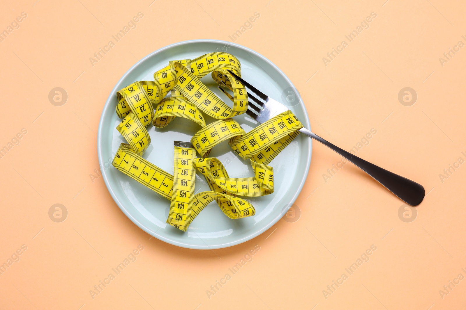 Photo of Measuring tape and fork on beige background, top view. Weight loss concept
