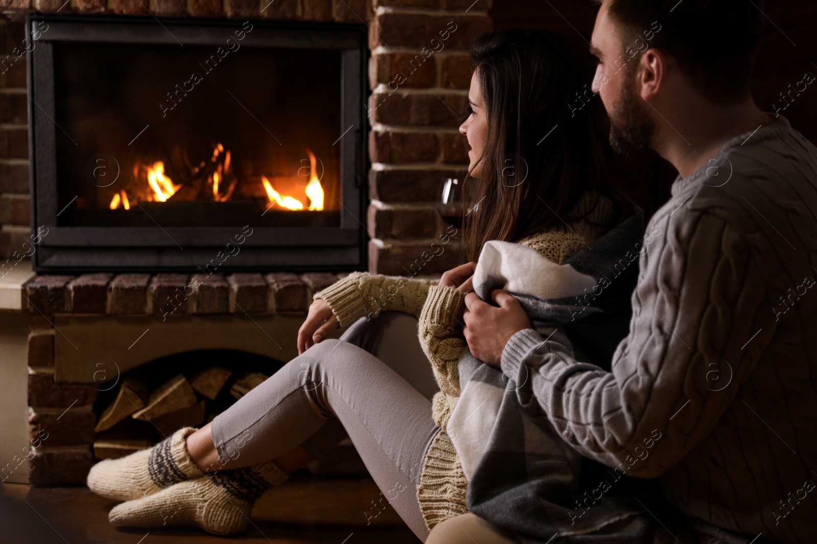 Photo of Lovely couple sitting on floor near fireplace at home. Winter vacation