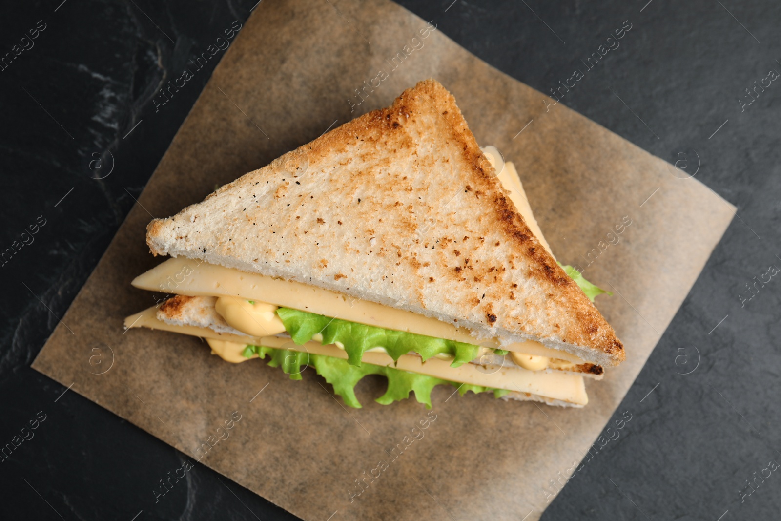 Photo of Fresh tasty cheese sandwich on black table, top view