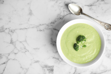 Photo of Delicious broccoli cream soup served on white marble table, flat lay. Space for text