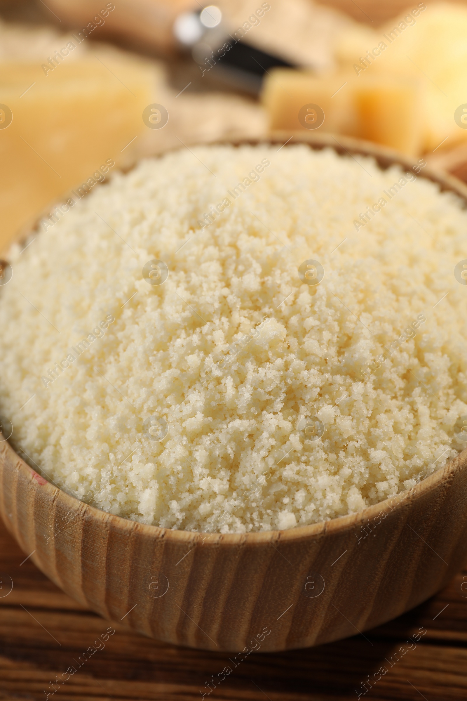 Photo of Bowl with grated parmesan cheese on wooden table, closeup