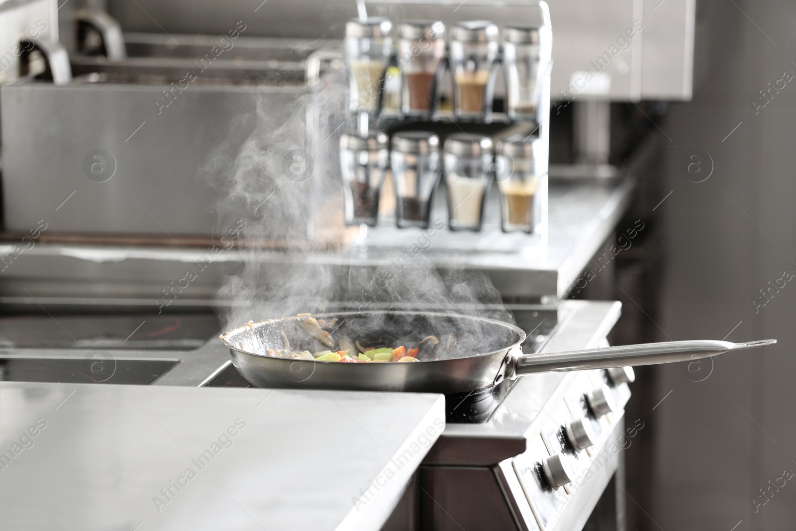 Photo of Cooking tasty food on stove in restaurant kitchen