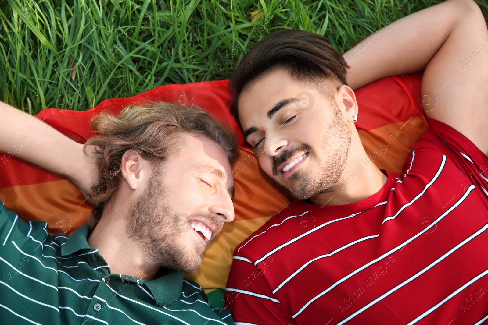 Photo of Happy gay couple lying on green grass, above view