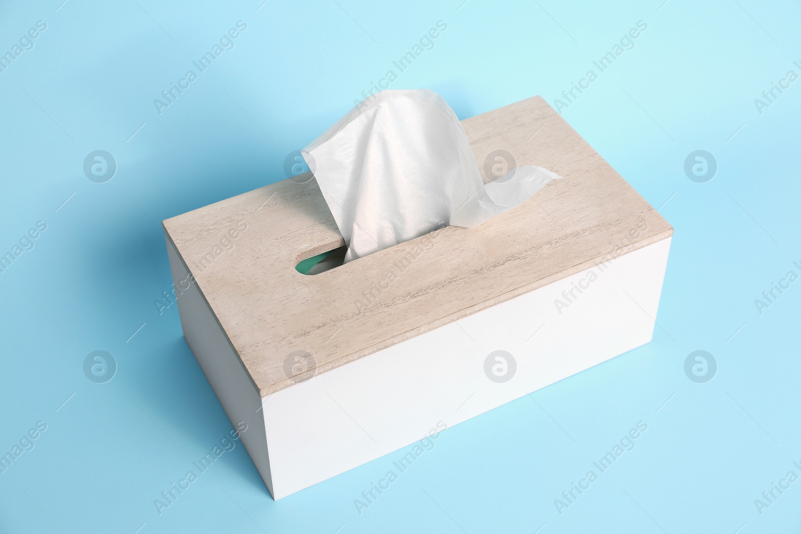 Photo of Holder with paper tissues on light blue background