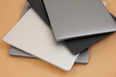 Photo of Different modern laptops on brown background, closeup