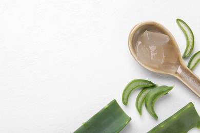 Photo of Aloe vera gel in spoon and slices of plant on white background, flat lay. Space for text