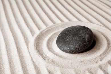 Zen garden stone on sand with pattern, space for text. Meditation and harmony