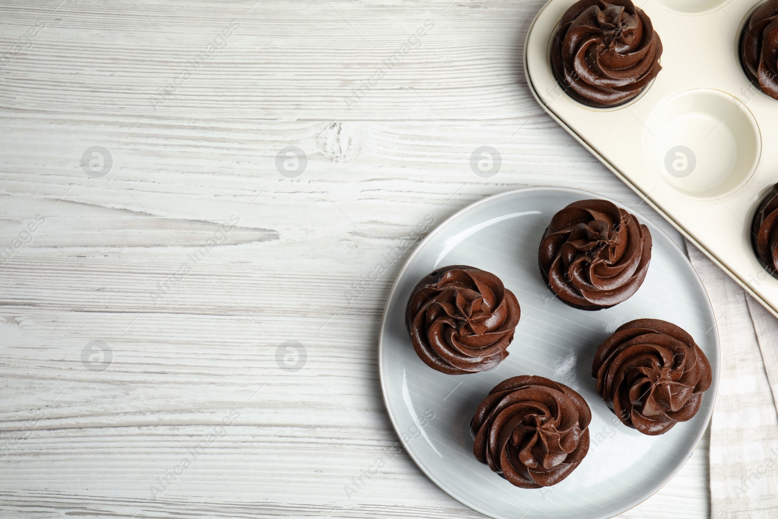 Photo of Flat lay composition with delicious chocolate cupcakes on white wooden table. Space for text