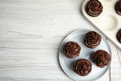 Flat lay composition with delicious chocolate cupcakes on white wooden table. Space for text