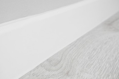 White plinth on laminated floor near wall indoors, closeup