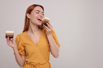 Young woman eating pieces of tasty cake on light grey background, space for text