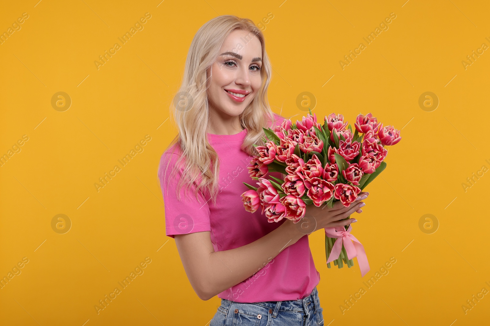 Photo of Happy young woman with beautiful bouquet on orange background