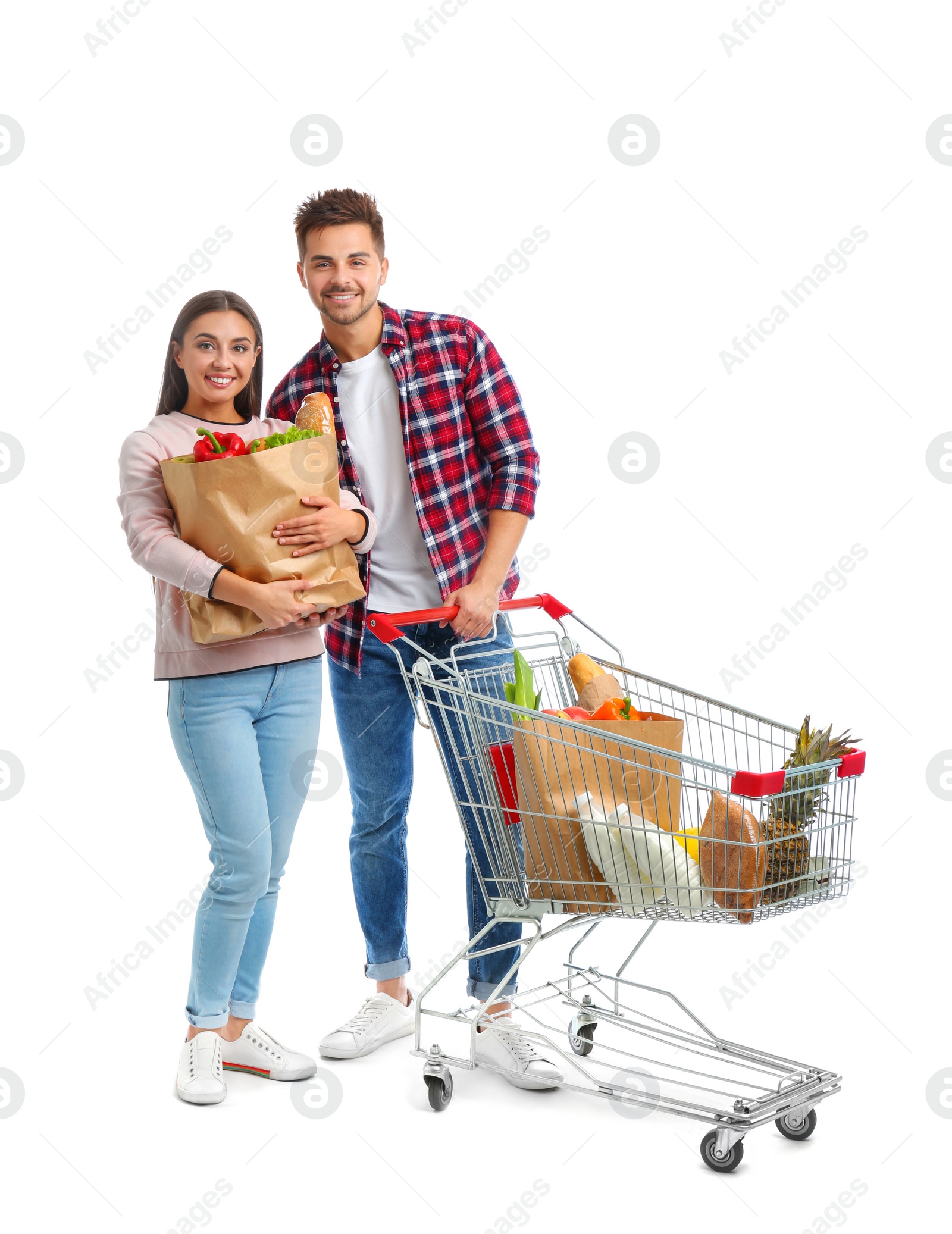 Photo of Young couple with full shopping cart and paper bags on white background