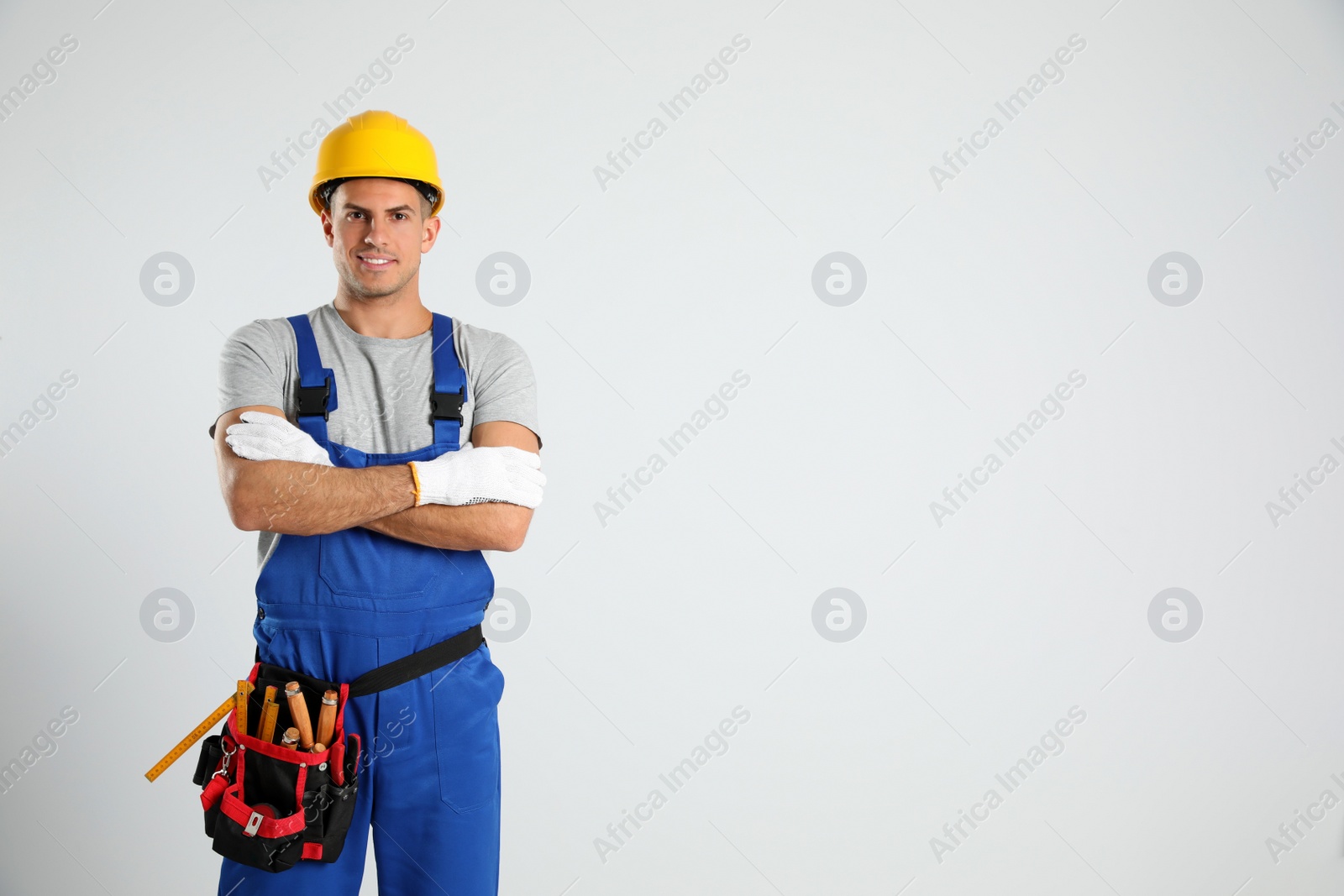 Photo of Carpenter with tool belt on light background. Space for text