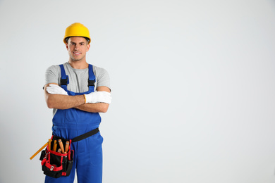 Carpenter with tool belt on light background. Space for text