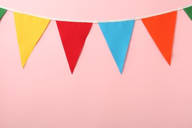 Bunting with colorful triangular flags on pink background. Space for text