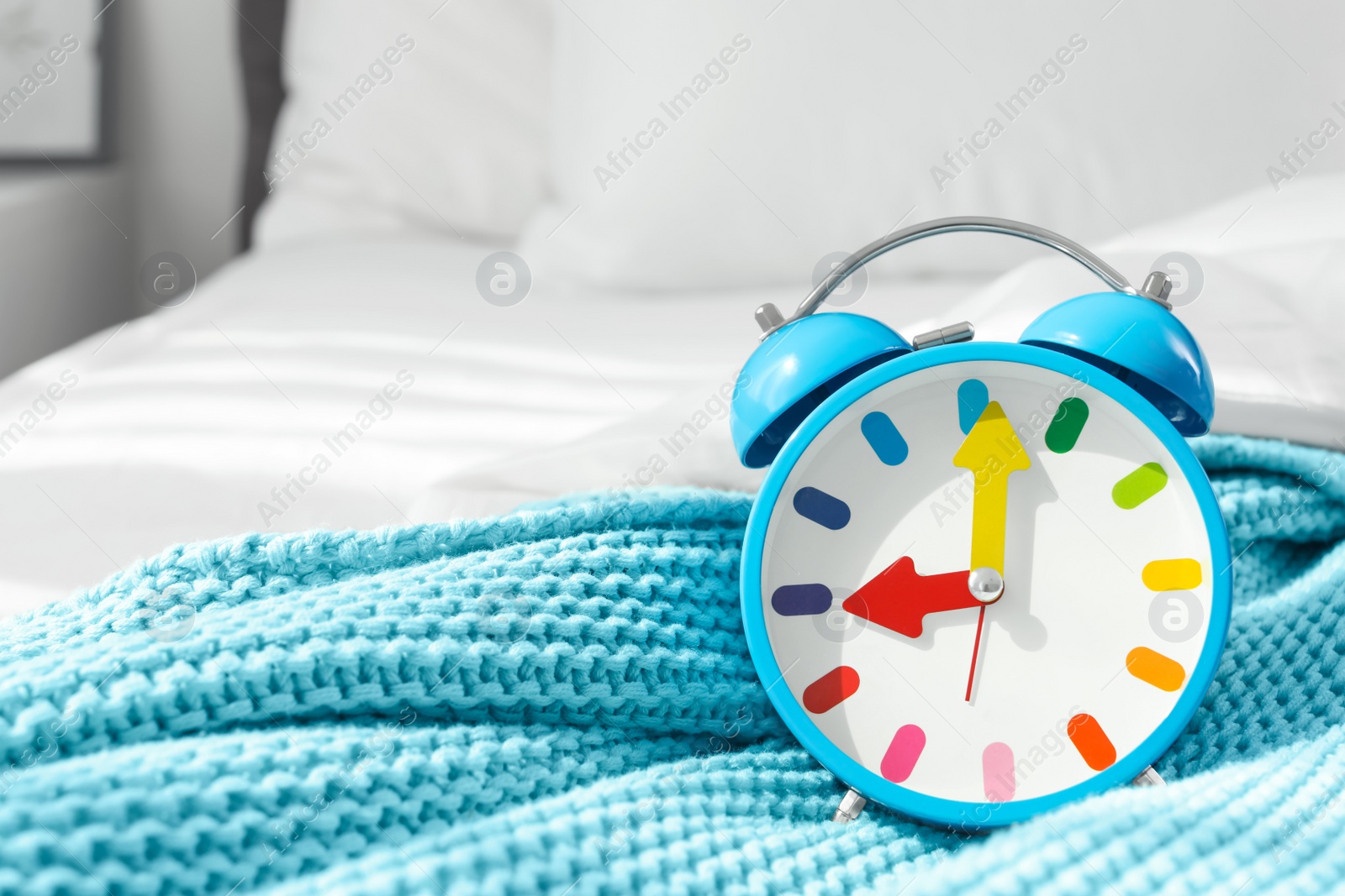 Photo of Colorful alarm clock on bed. Time to wake up