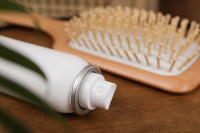 Photo of Dry shampoo spray and hairbrush on wooden table, closeup